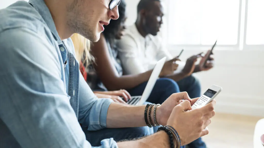 College students sitting on their devices.