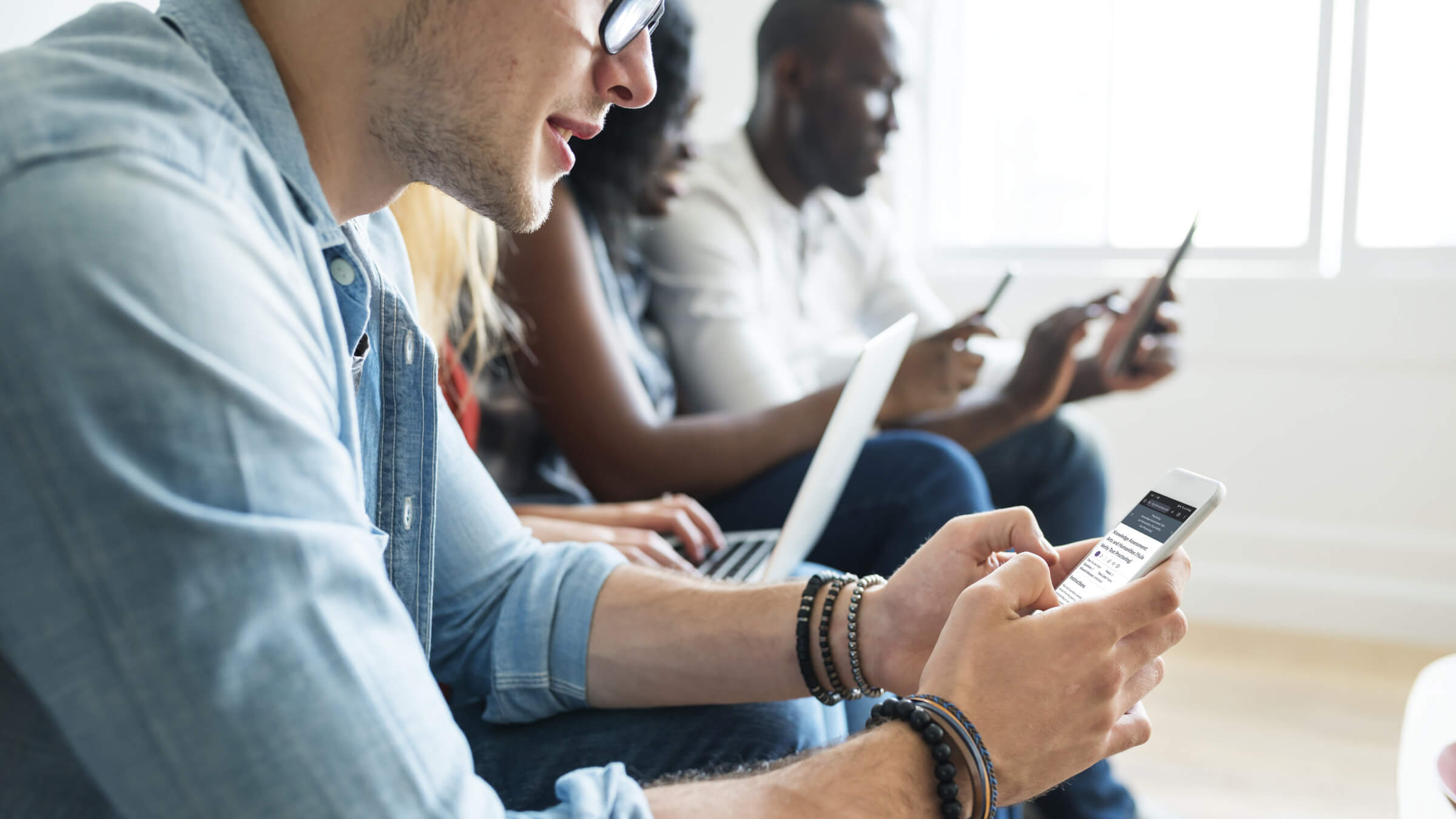 College students sitting on their devices.