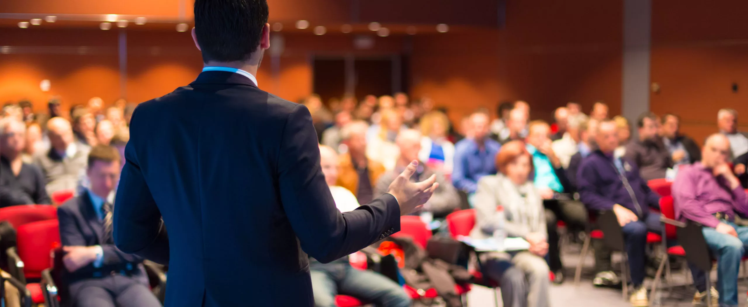 A man in a suit presenting to an audience.