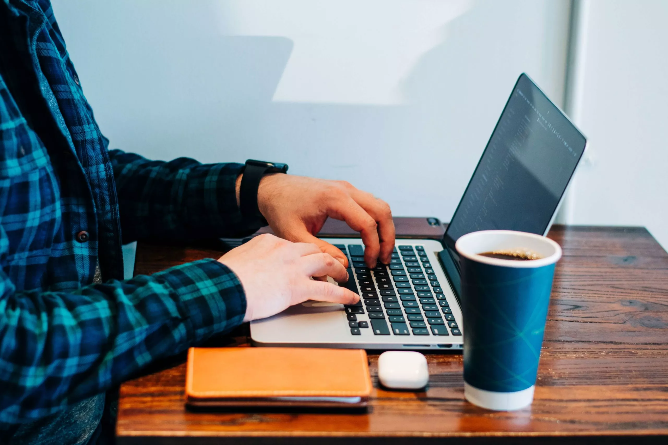 A man typing on a laptop at a table, focused on his work.