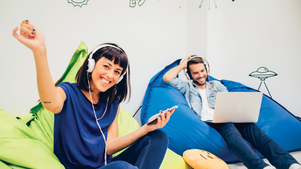 A couple enjoying music together while sitting on bean bags.