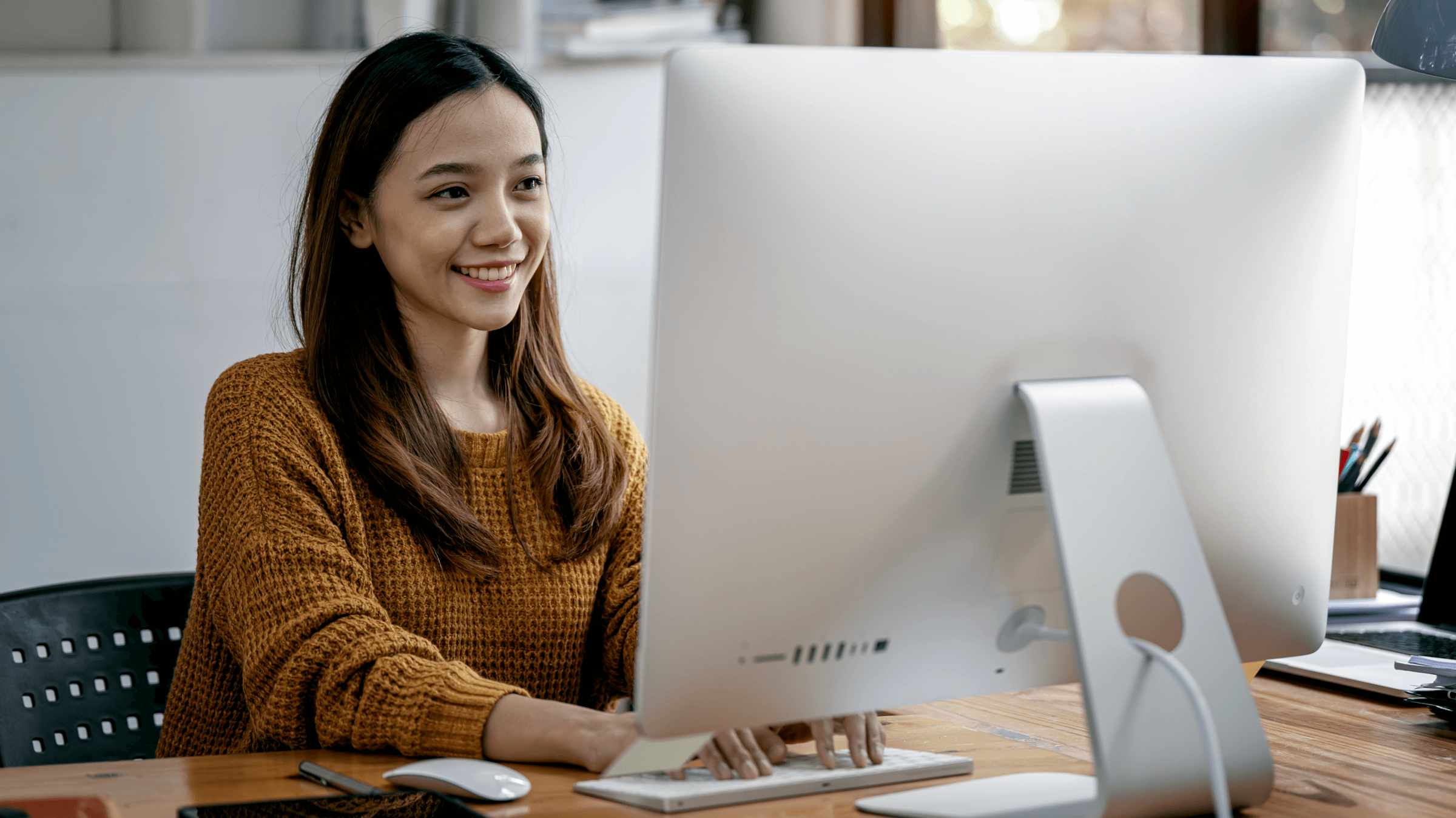 A woman smiles as she uses her computer.