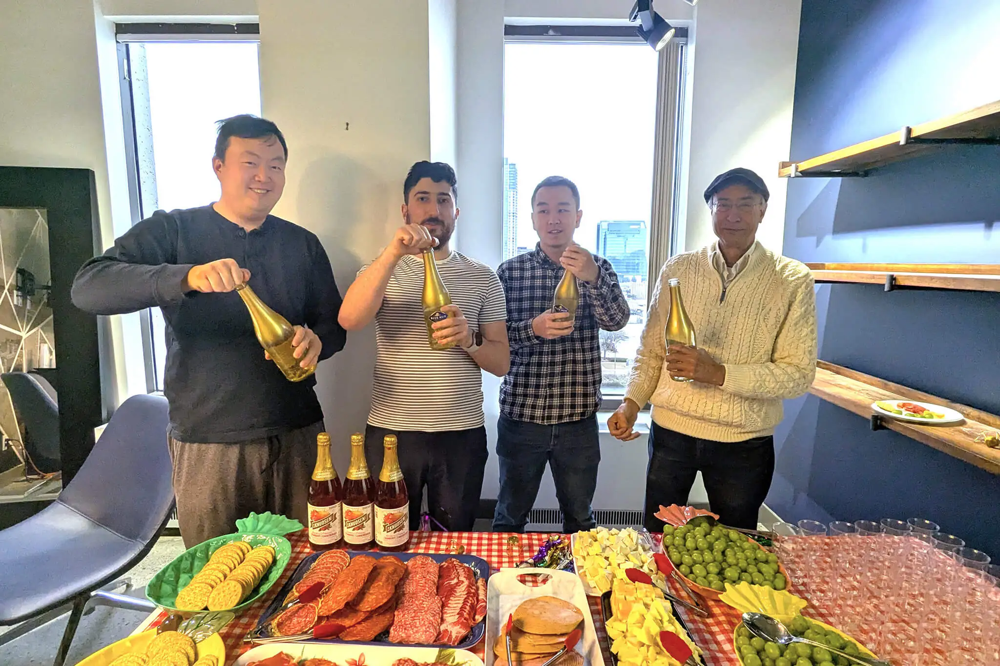 A group of four men from YuJa standing around a table, enjoying food and drinks together in a social setting.