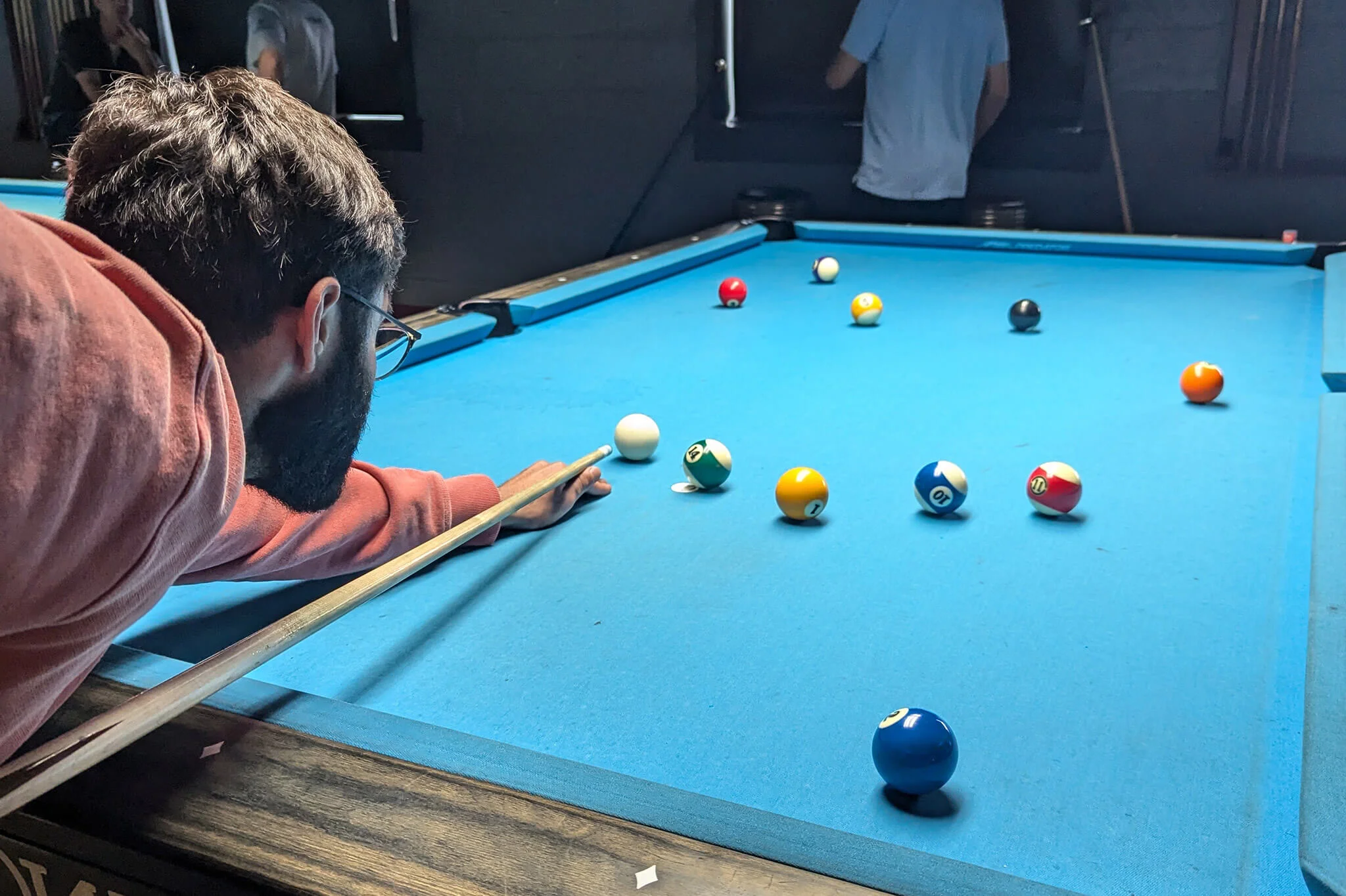 A man from YuJa's team is focused on playing pool.