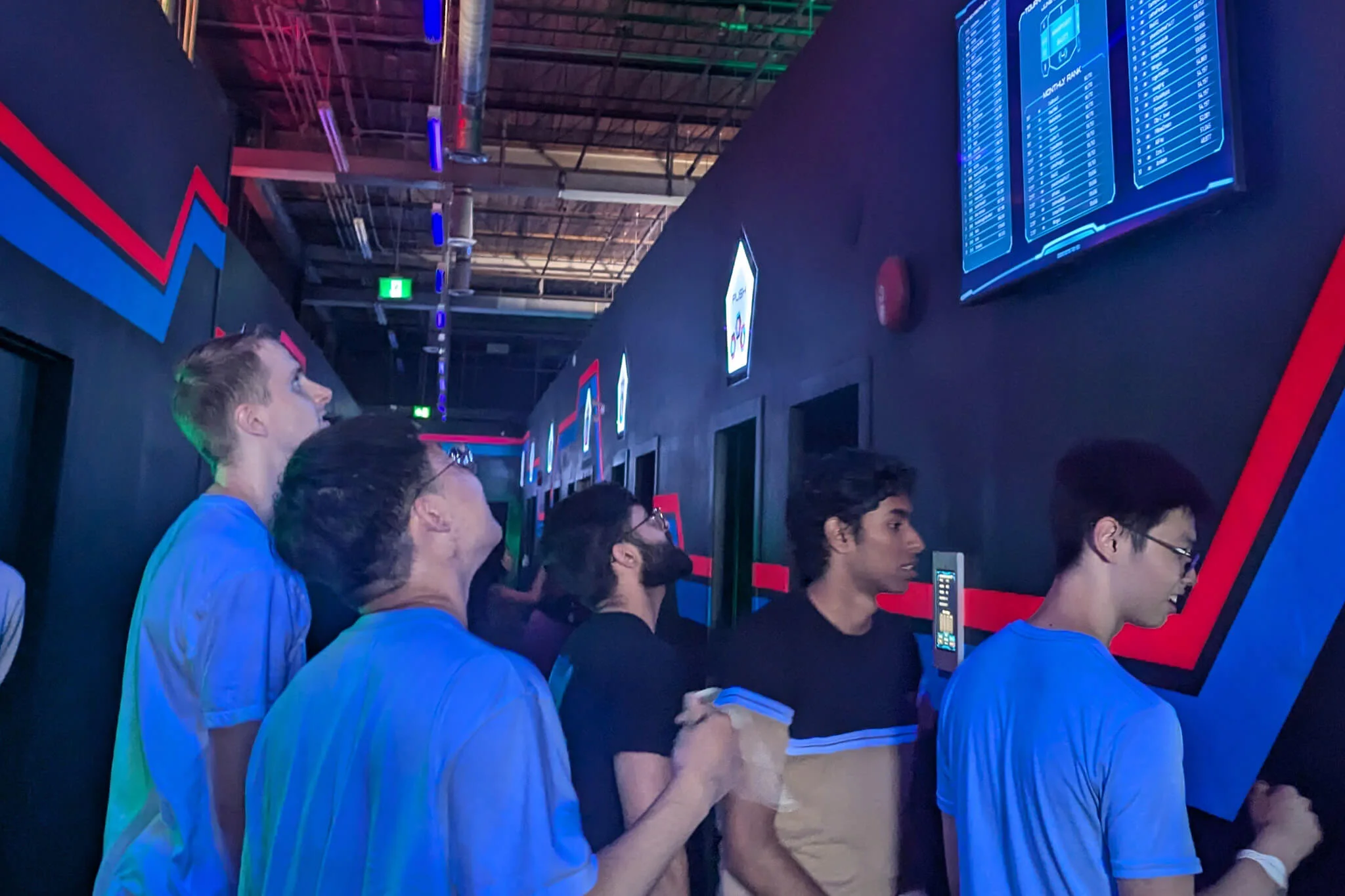 YuJa team members standing together in front of a video game, highlighting teamwork and shared interests in gaming.
