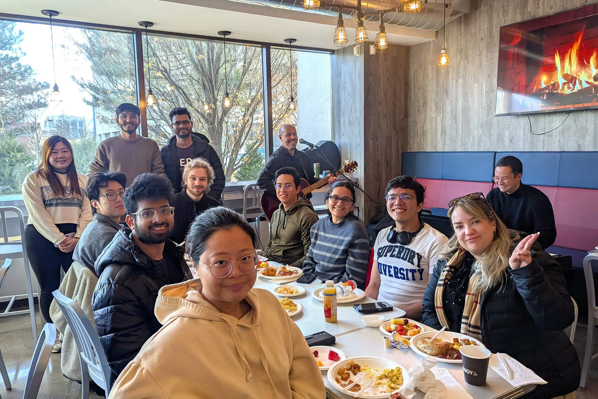 A group of YuJa team members gathered around a table enjoying a meal together, sharing food and conversation.