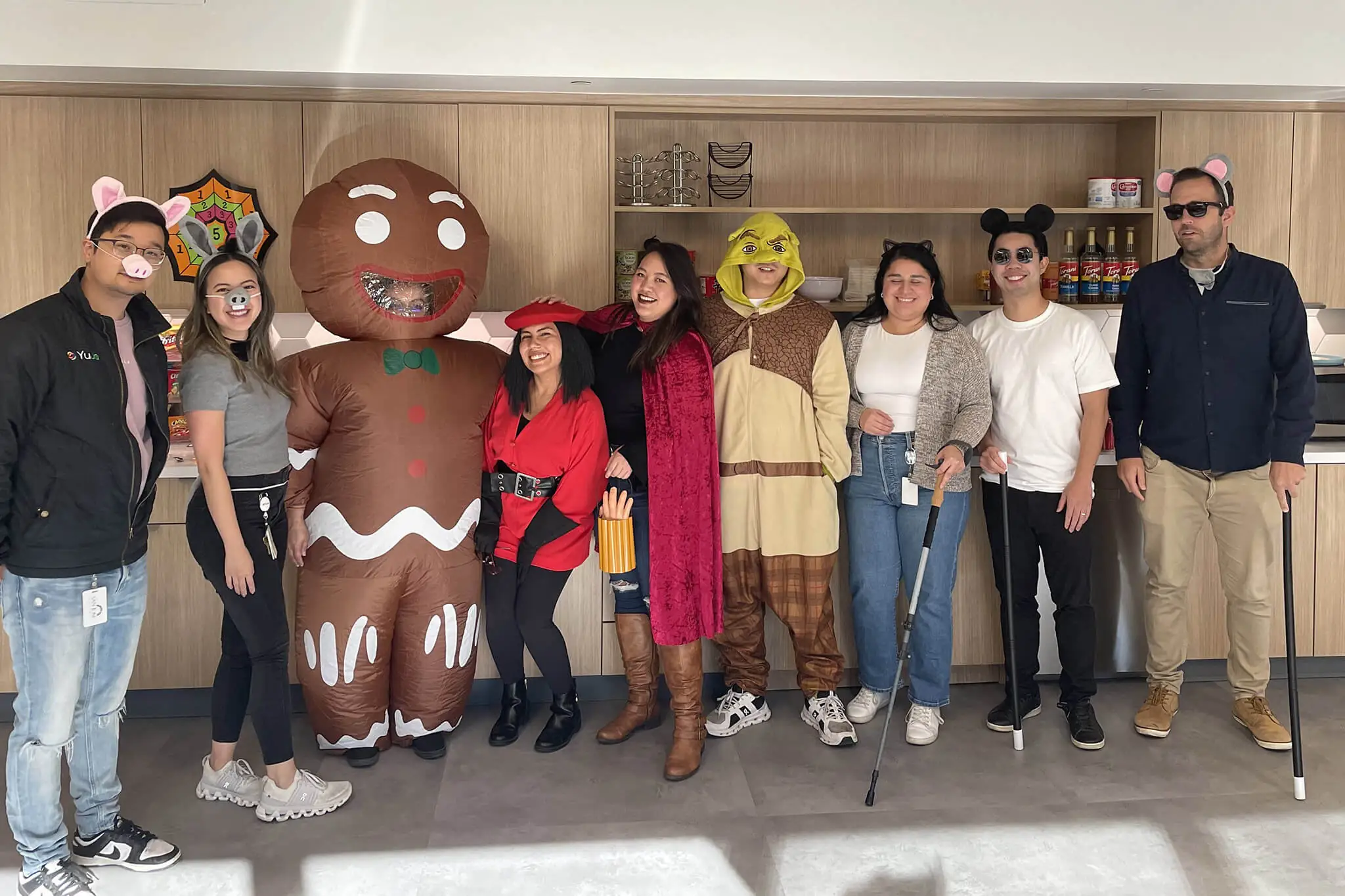 A group of YuJa team members joyfully posing with a large gingerbread man during a festive celebration.
