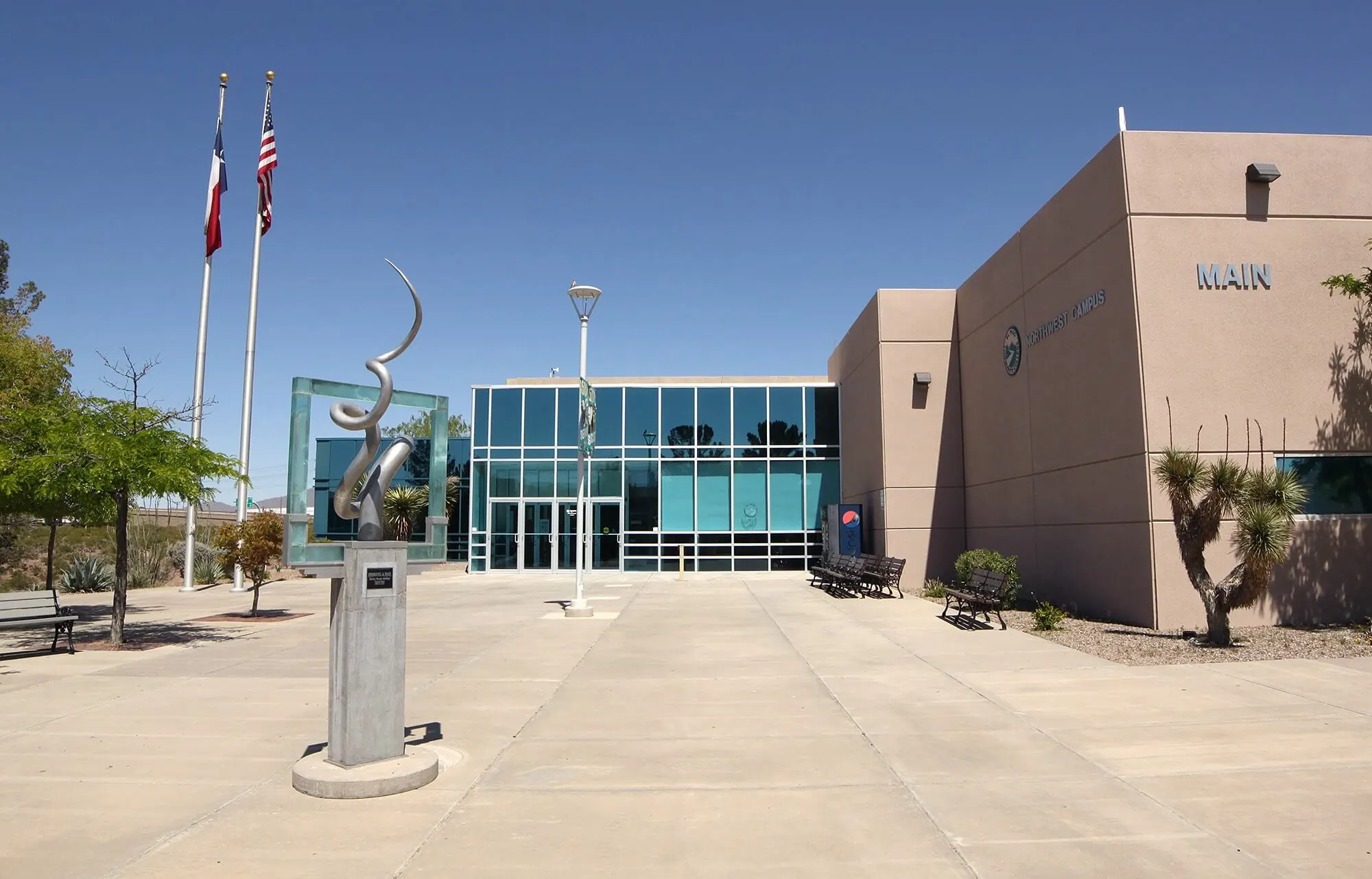 El Paso Community College building and quad with flagpoles and a statue prominently featured.