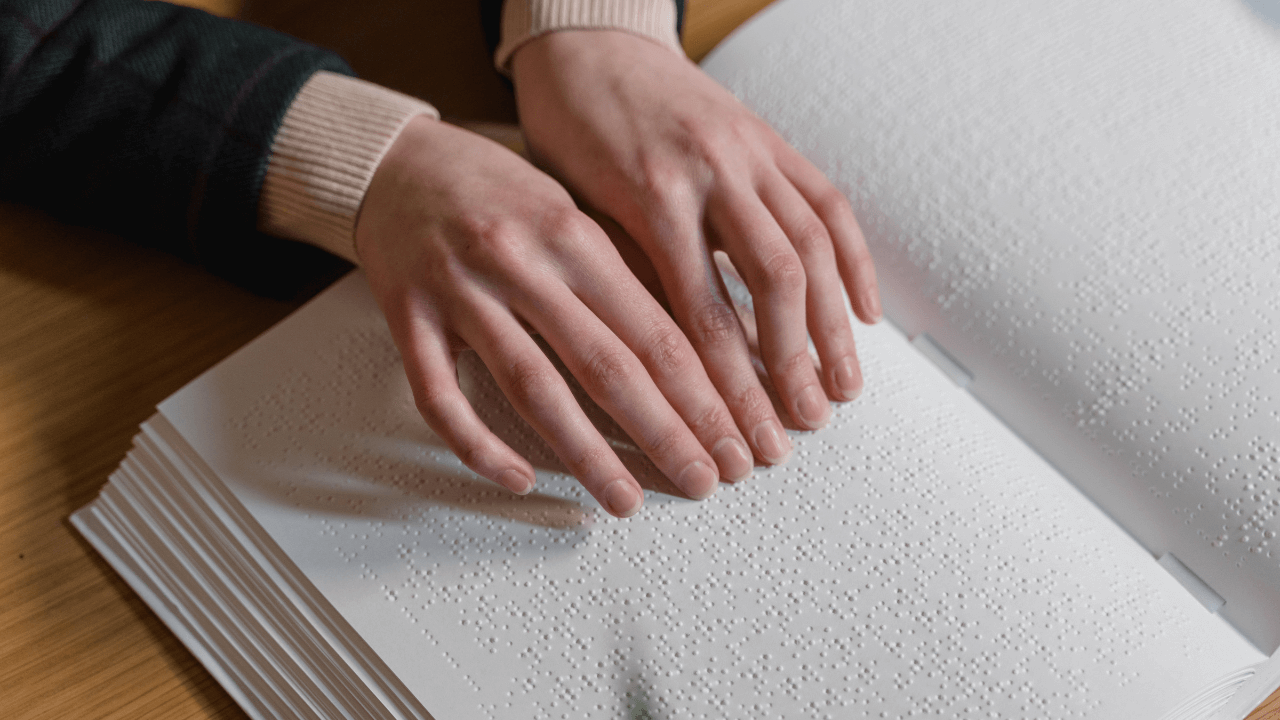An image showing hands over a Braille book.