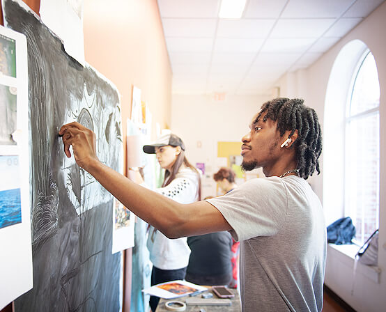 A student engaged in artistic expression on a blackboard at Belhaven University's art class.