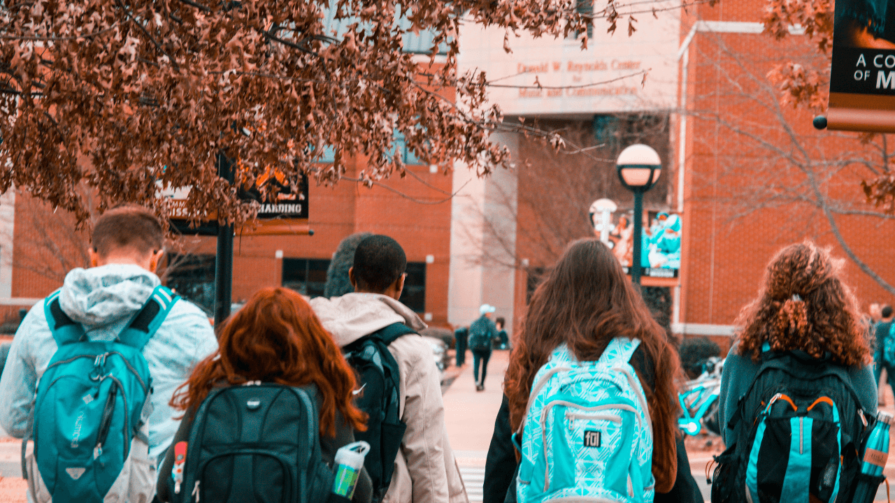 A diverse group of students walking down the sidewalk on a sunny day.