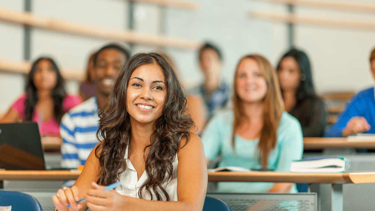 A smiling student surrounded by classmates in a classroom.