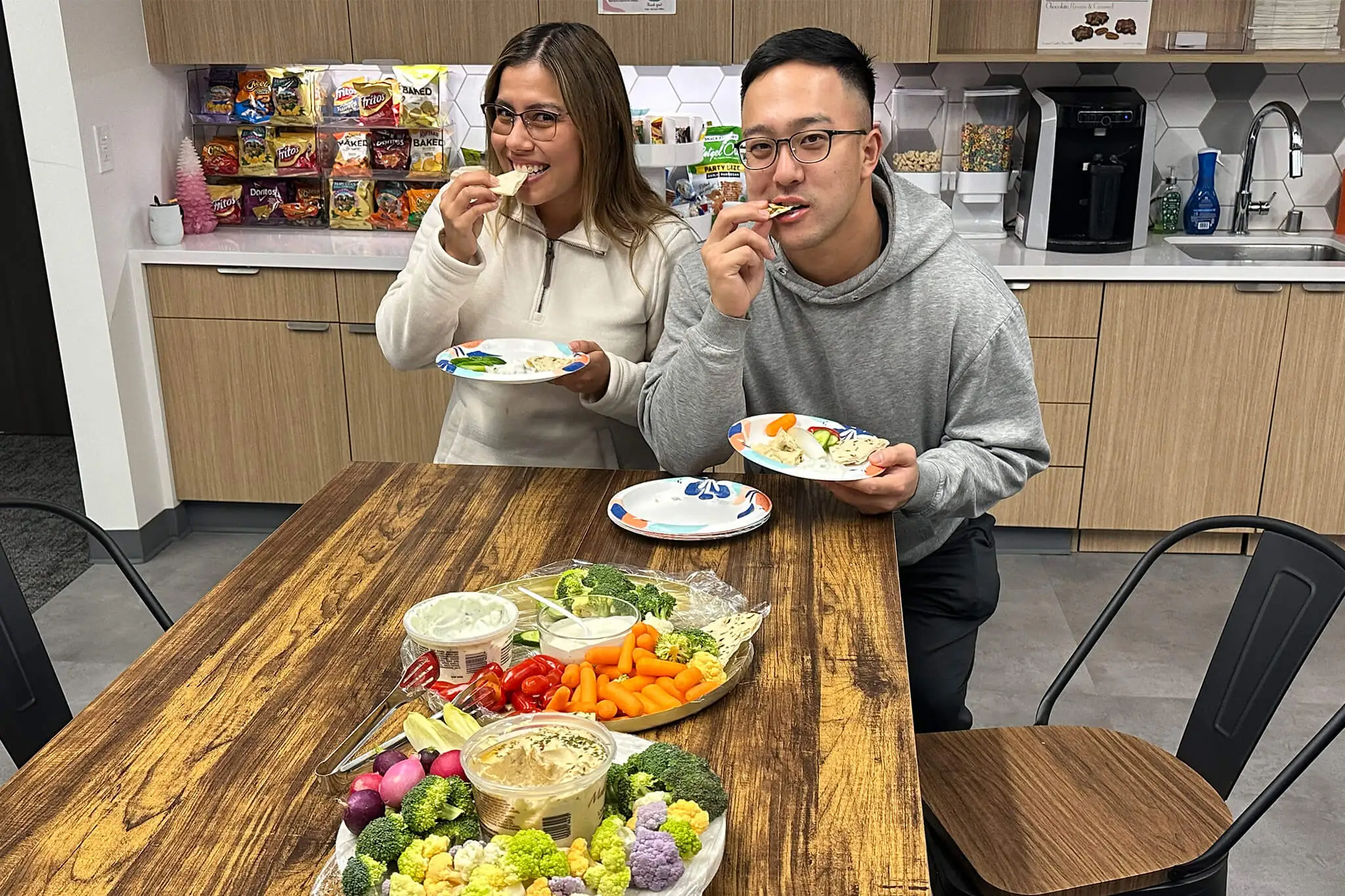 Two members of YuJa's team members enjoying a meal together at a table, sharing food and conversation.