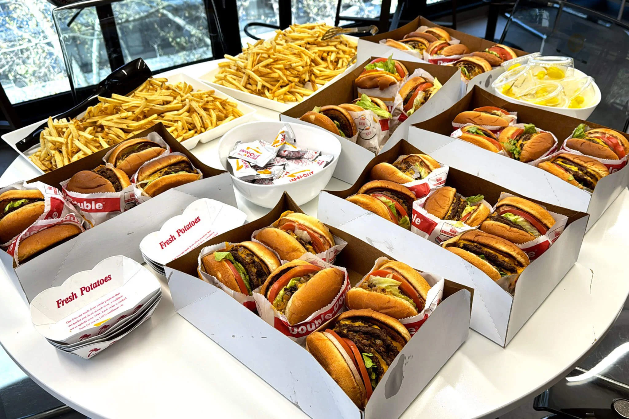 A table filled with an assortment of hamburgers and fries, enjoyed by YuJa's team members during a gathering.