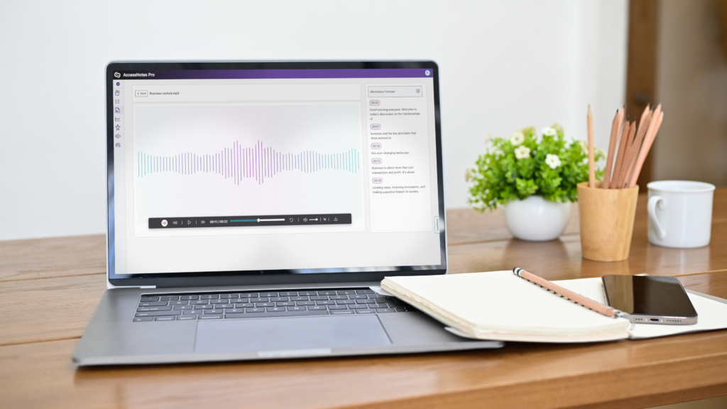 A laptop running AccessNotes PRO sits on a desk along with a notepad.