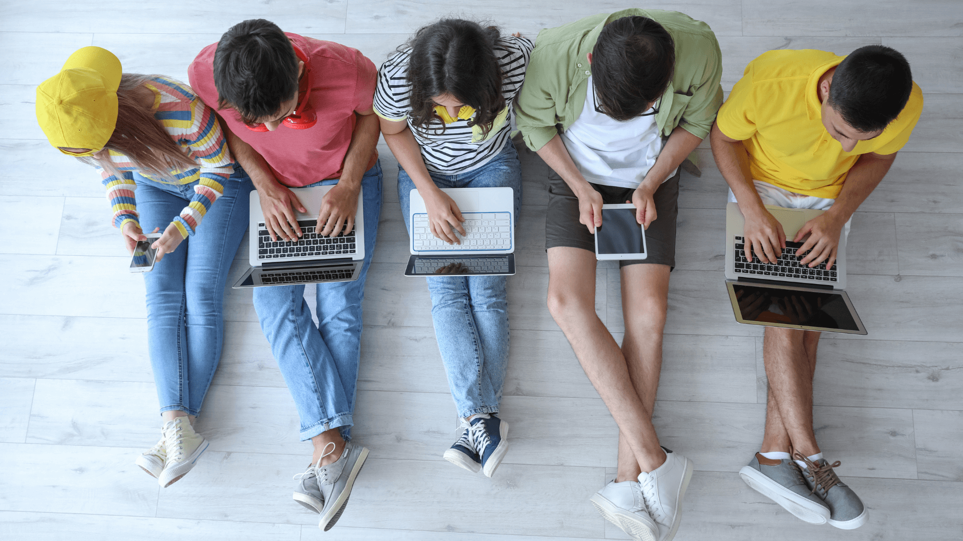 Five people sitting on the floor with laptops, engaged in work or study.