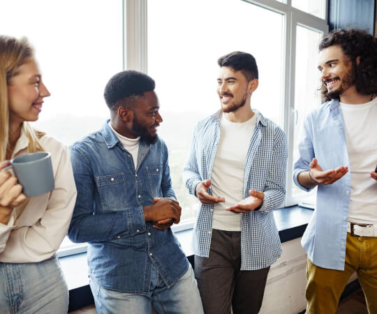 Three people standing together, smiling and talking.