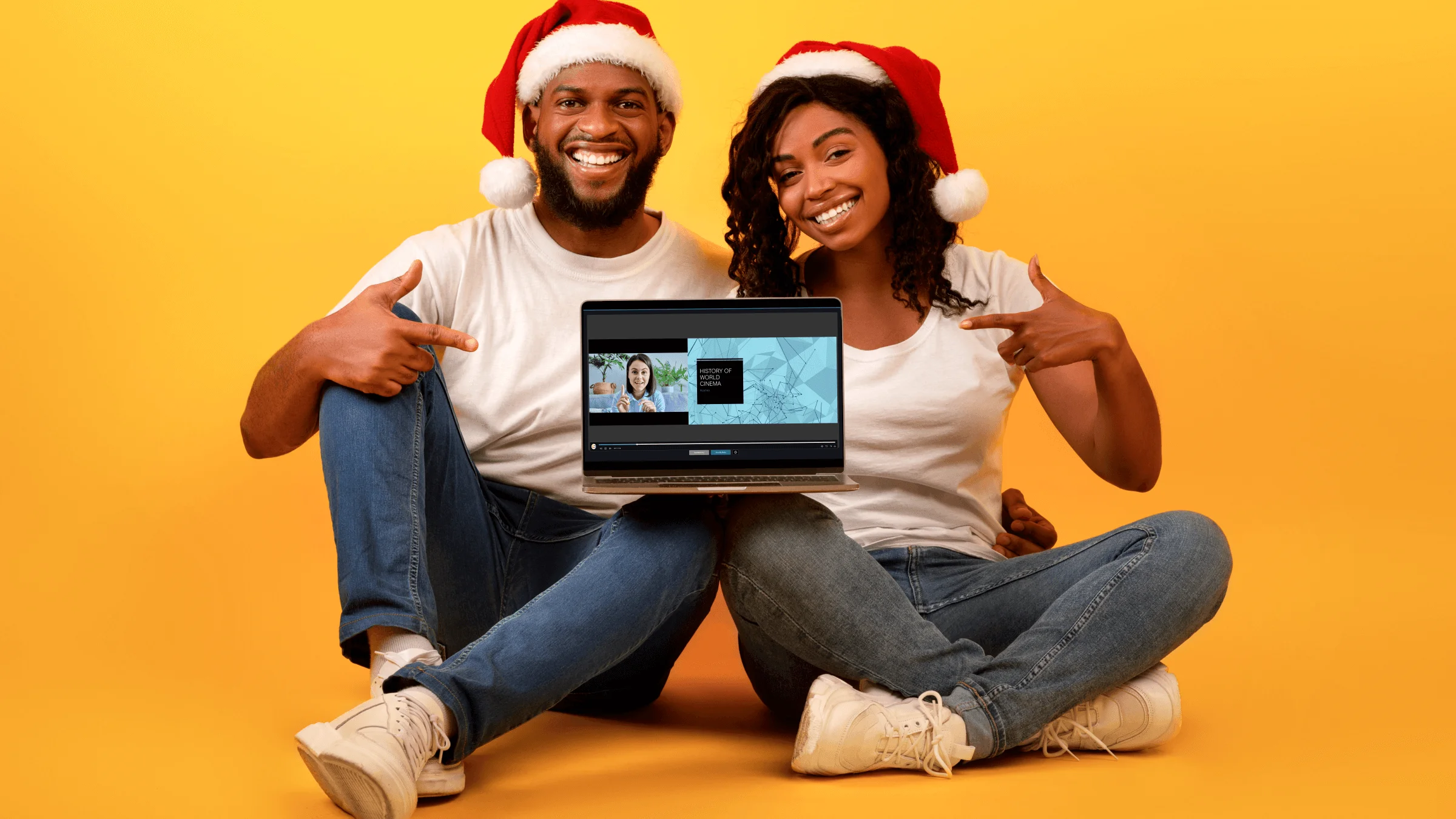A couple wearing matching Santa hats sits with a laptop propped up on their knee, pointing to what's on the screen, which is the new Browser Capture Studio.