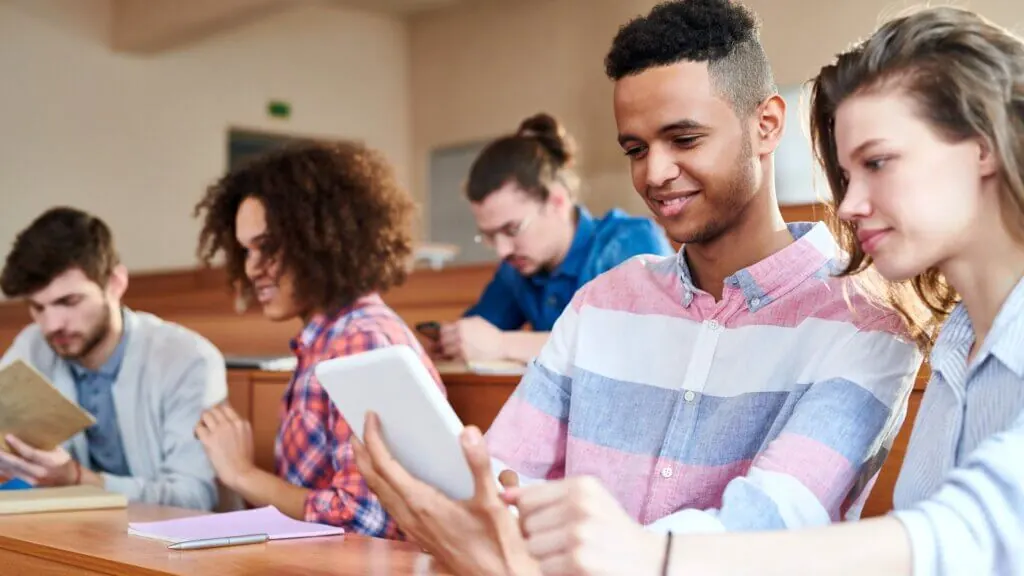 College students engage in the classroom using their devices.