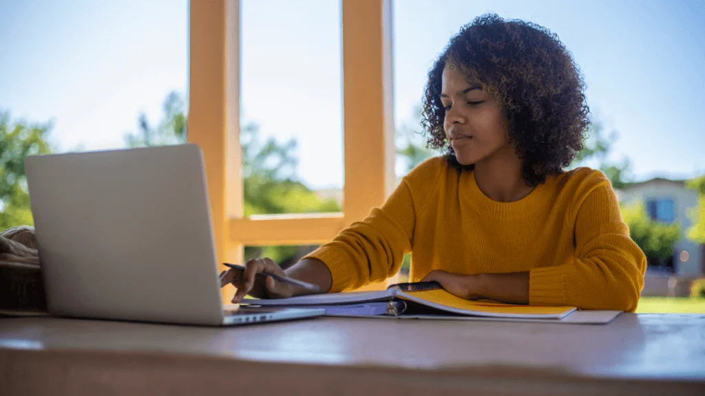 Woman sits at table with laptop.