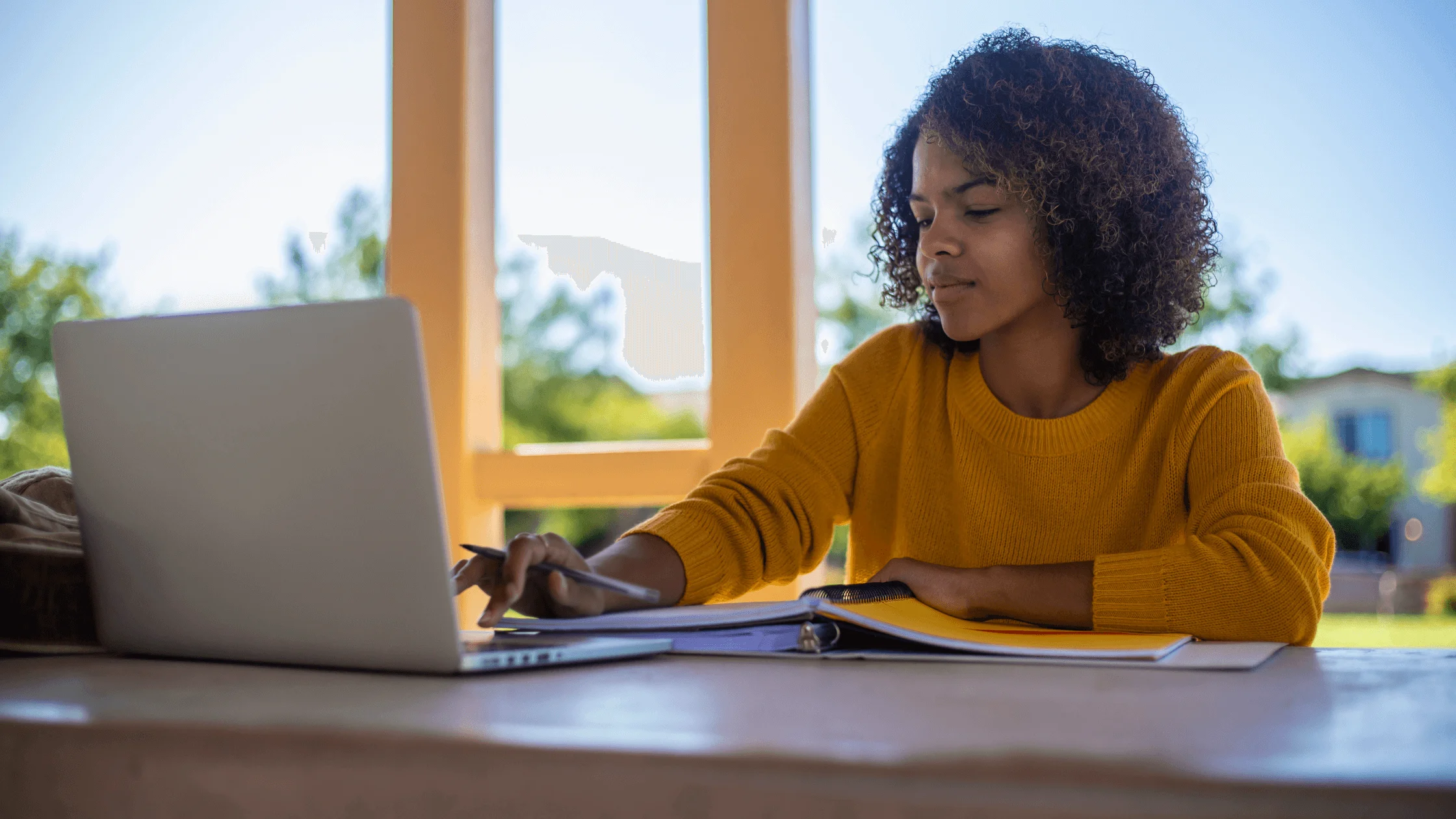 Woman sits at table with laptop.