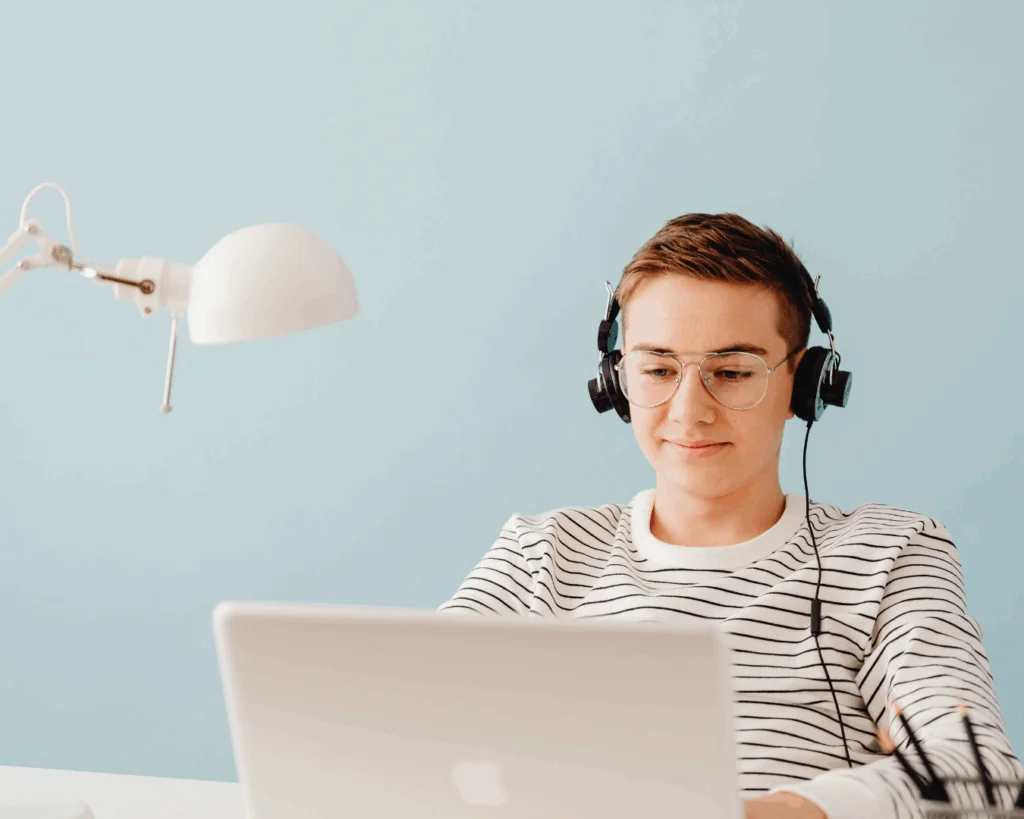 A student is listening to headphones at a laptop.