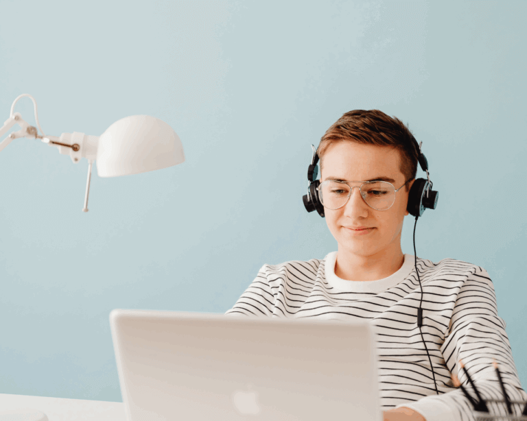A student is listening to headphones at a laptop.