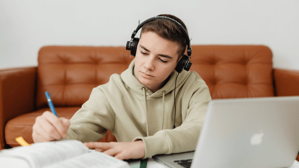 Student listening to an assignment on a laptop with headphones
