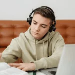 Student listening to an assignment on a laptop with headphones