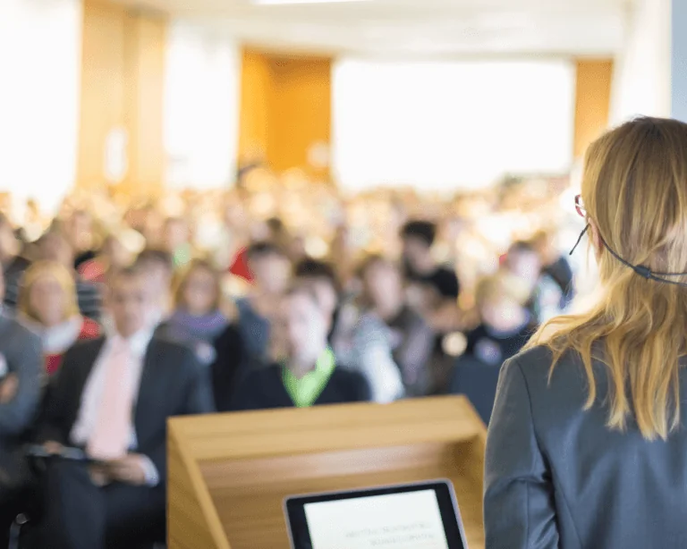 A lady speaks to a crowd at a tech conference