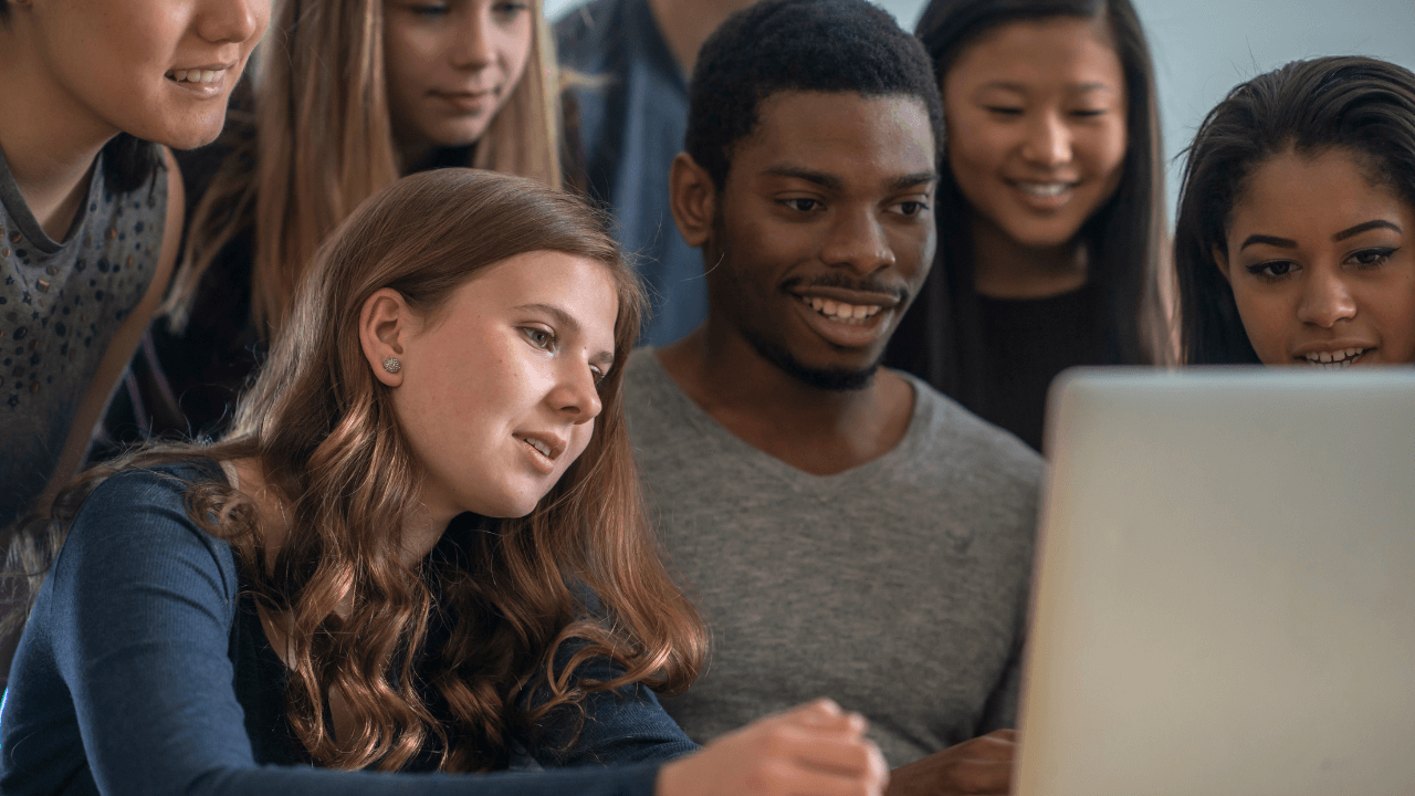 A group of students gathered around a laptop