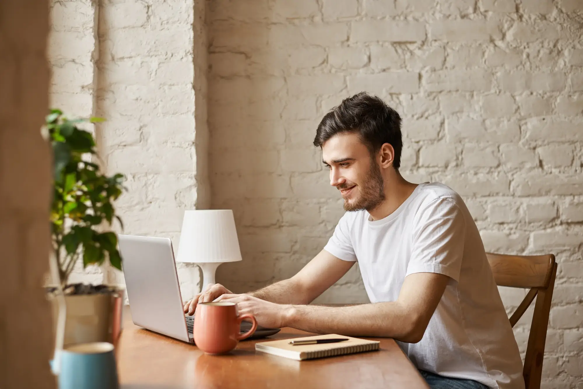 A man sitting at a table with a laptop, engaged in online learning.