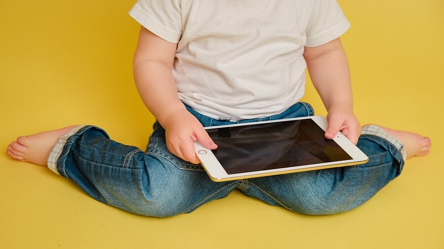 Toddler With Apple Ipad Digital Tablet On Studio Yellow Background