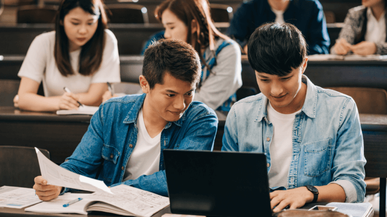 Two students looking at a laptop in a classroom.