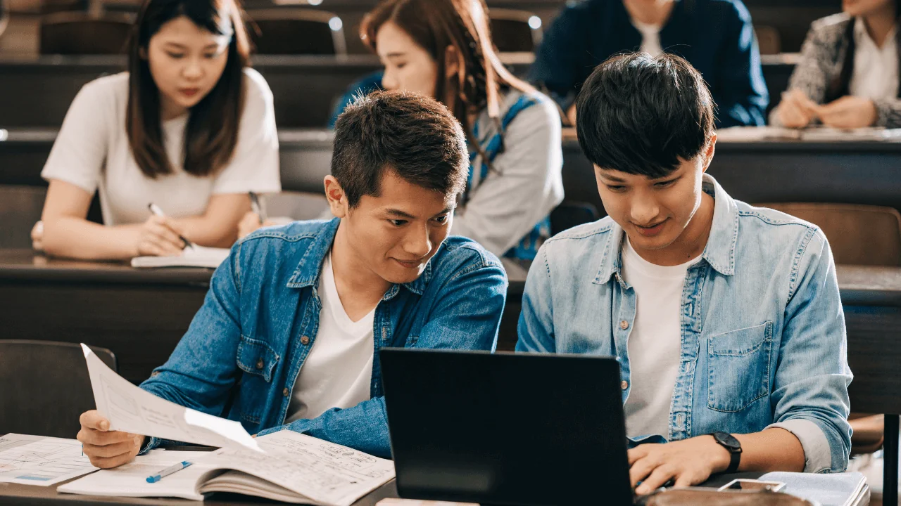 Two students looking at a laptop in a classroom.