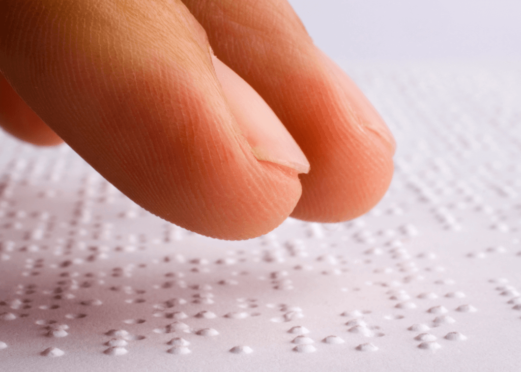 Finger tips on a sheet of Braille