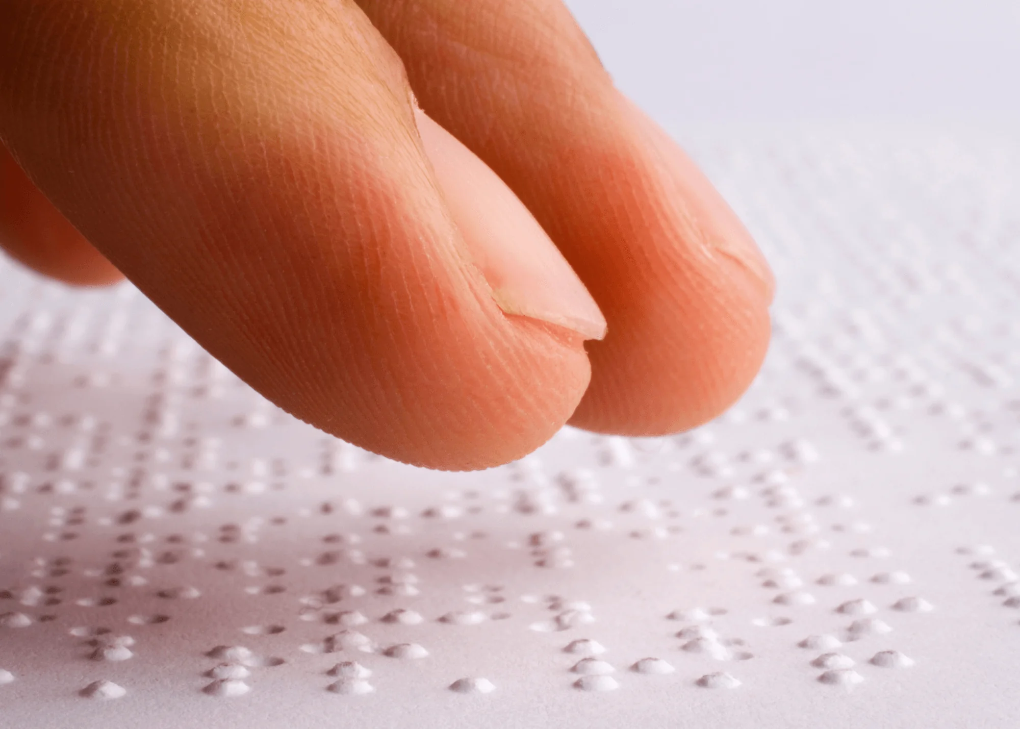 Finger tips on a sheet of Braille