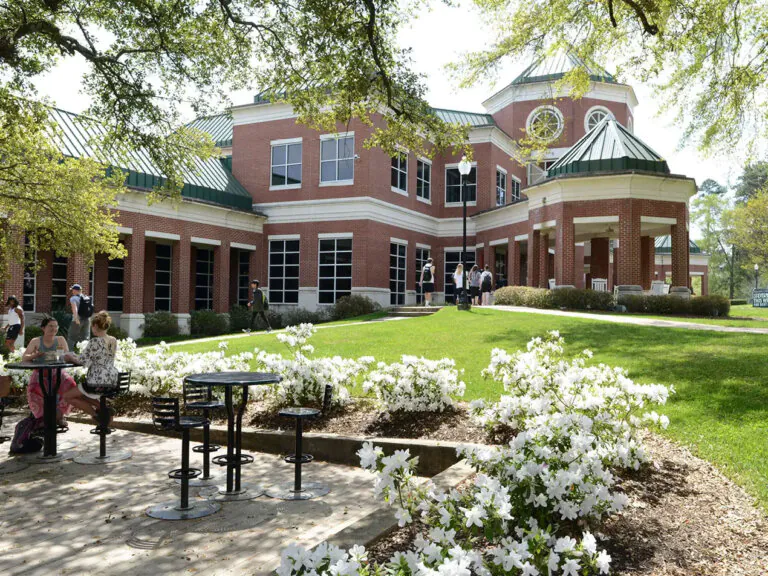 A view of Belhaven University with benches and tables beside it.