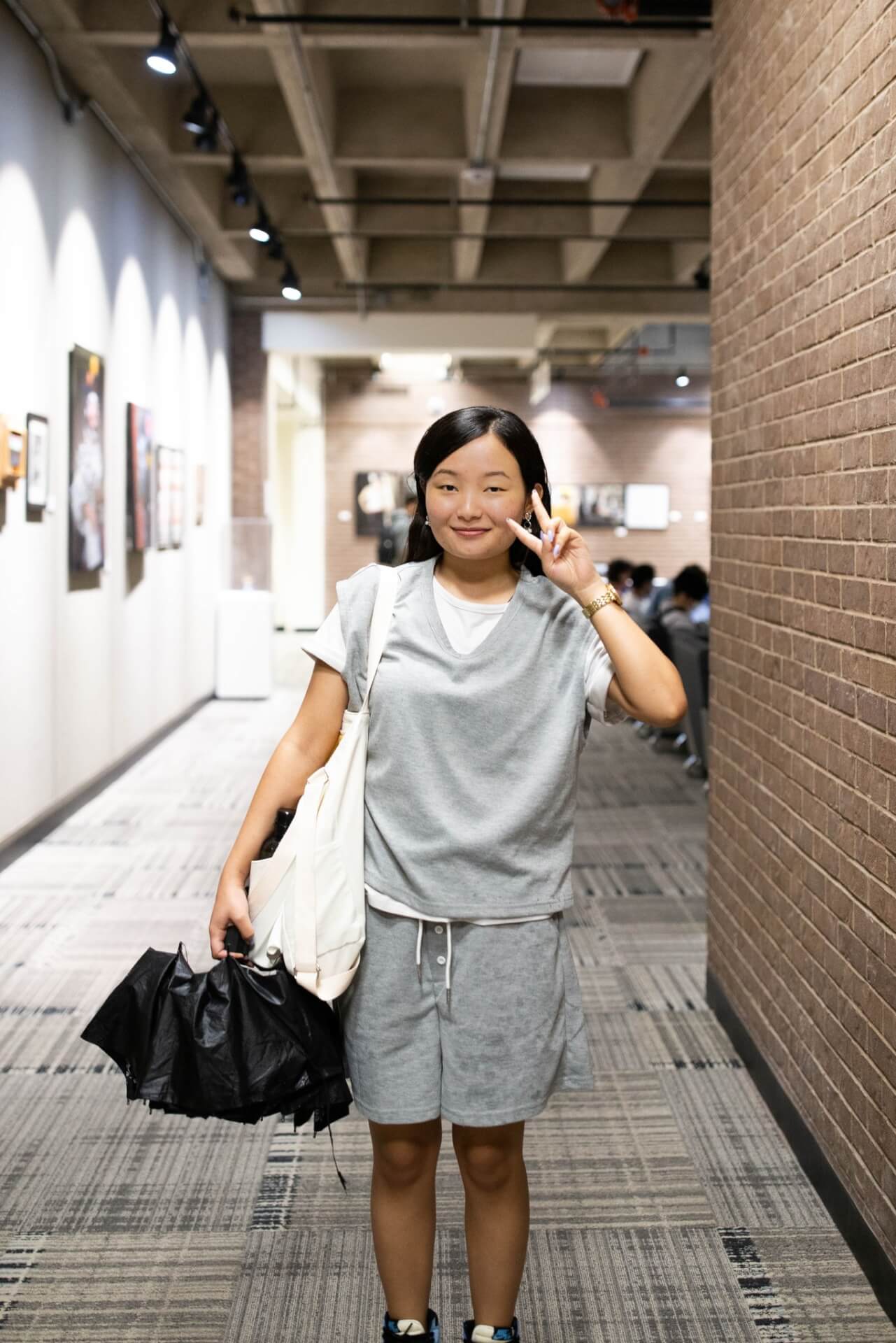 A woman in a gray shirt and shorts standing in an art gallery.