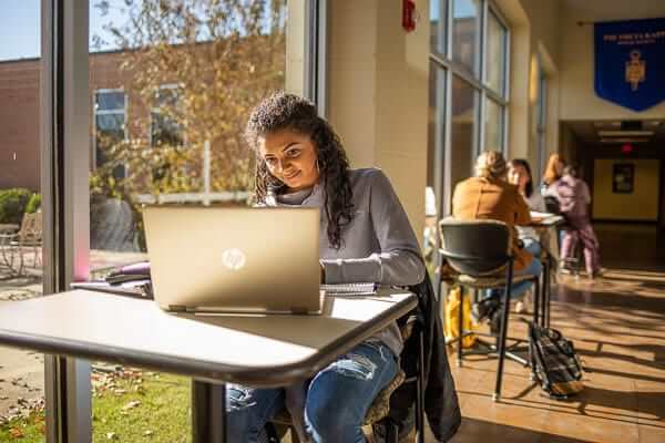 A student looks at their laptop. 
                