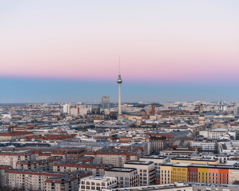 Berlin skyline at sunset, showcasing iconic landmarks like Brandenburg Gate and TV Tower.