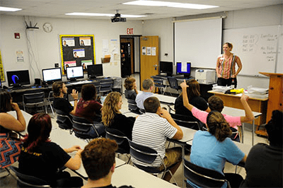 A teacher instructing students in a classroom setting.