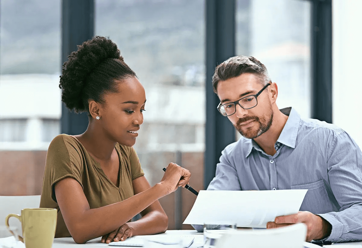 Two people look at a document together. 