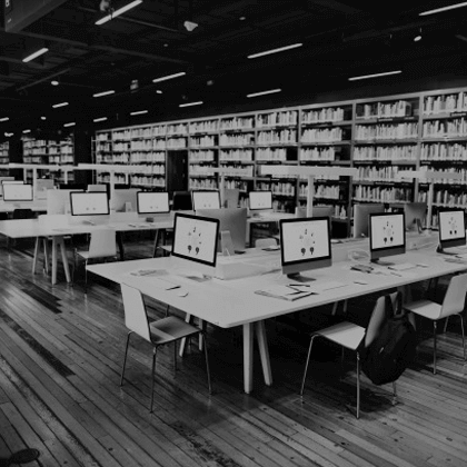 A monochrome image of a library filled with computers.
