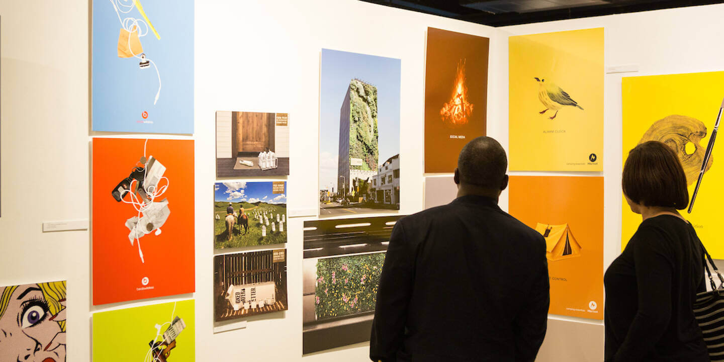 People admiring artwork at ArtCenter College of Design exhibition.