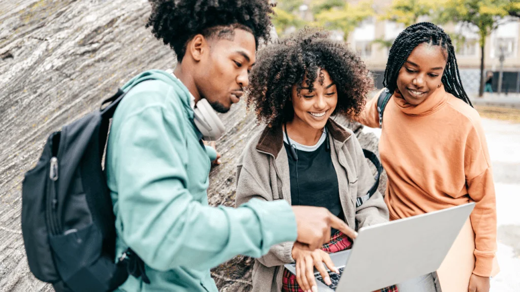 Three college students looking at a laptop