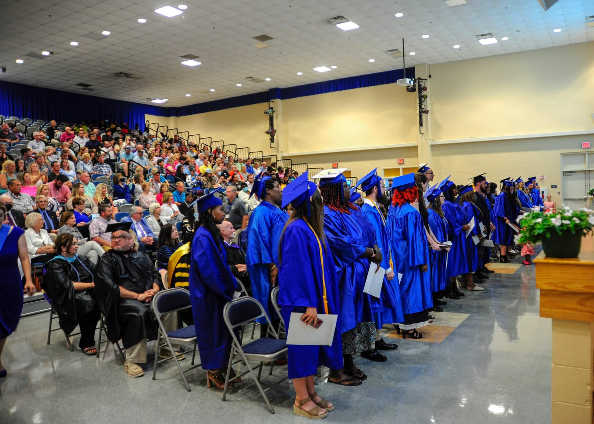 Graduates in blue gowns stand in a line in Pamlico Community College.