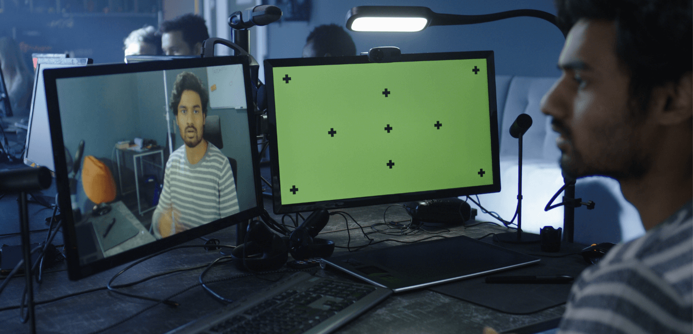 Man records self in front of two computer monitors.