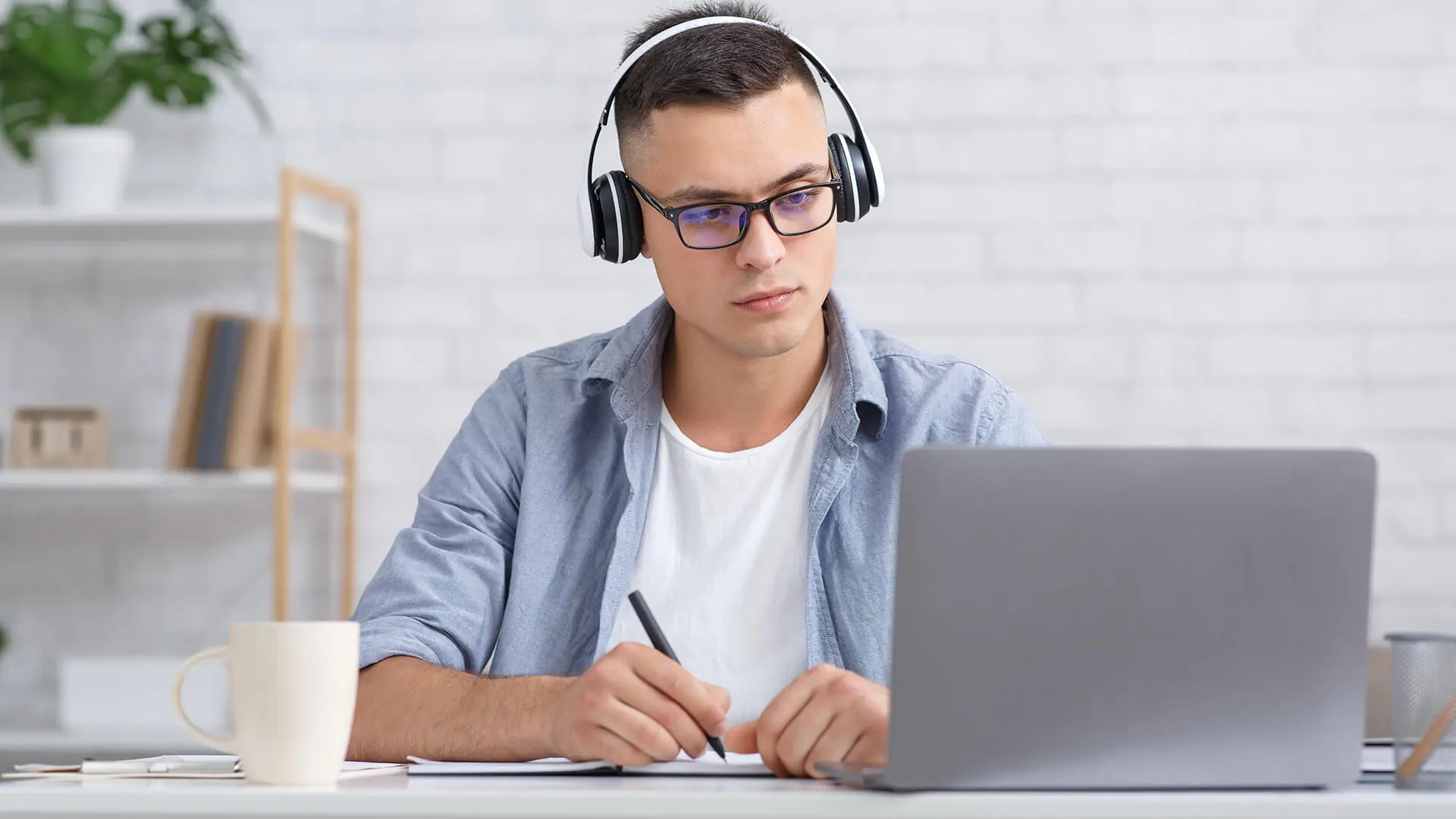 A young man wearing headphones looks at a computer.