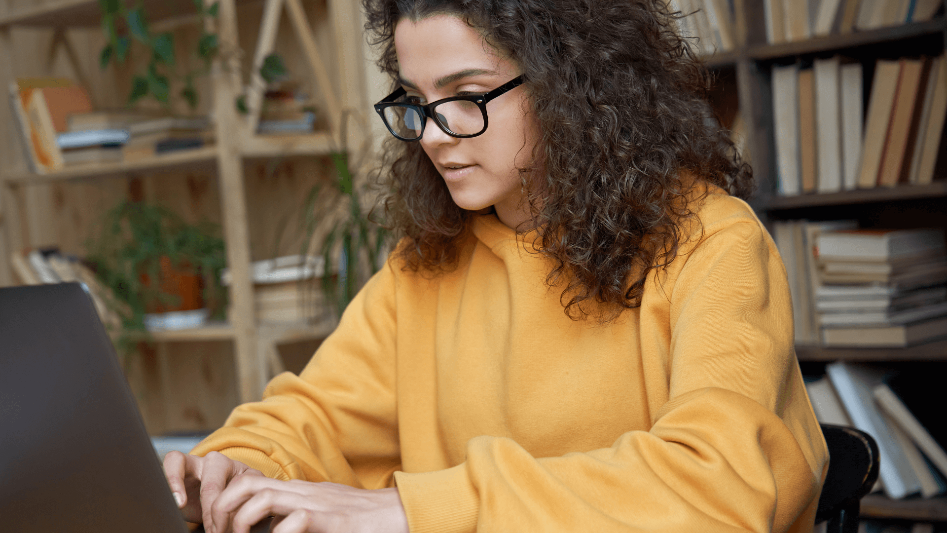 student in glasses looking at a laptop